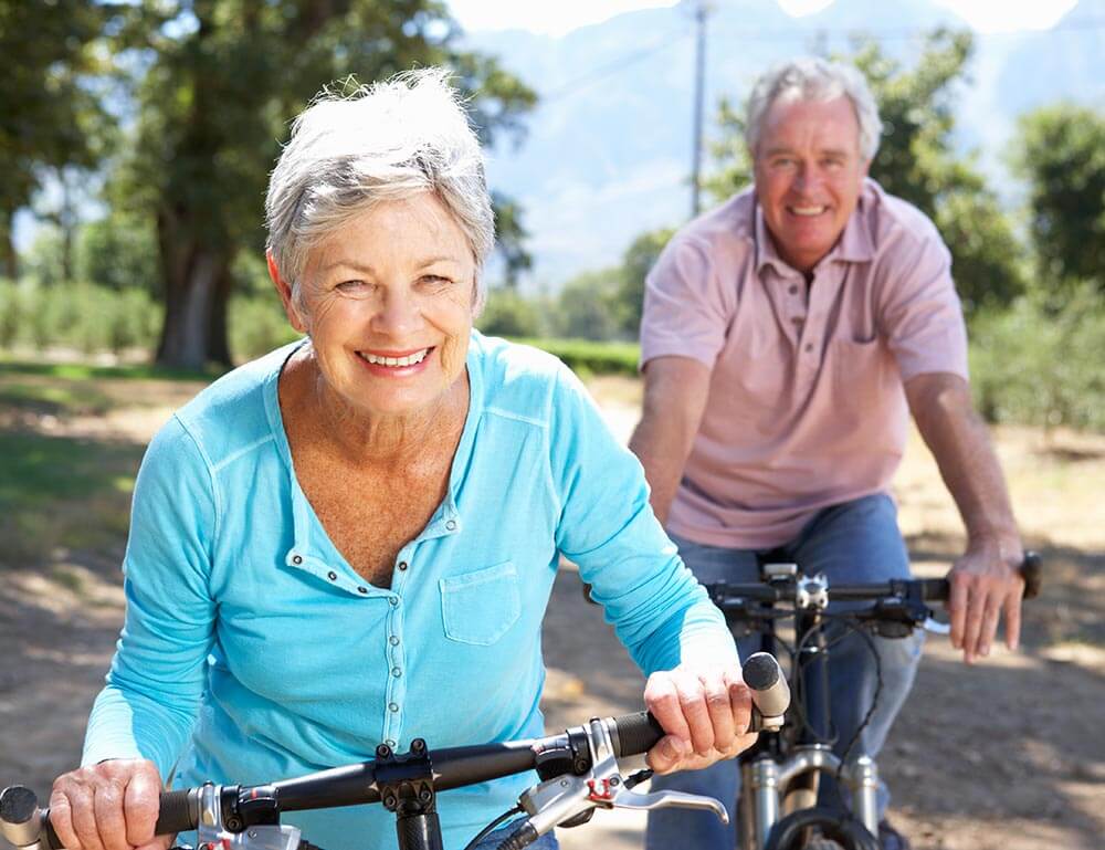 Happy older man and woman riding bike outside